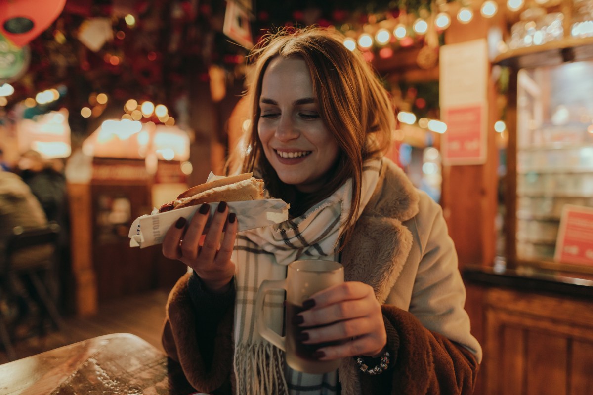 Woman trying out local specialties at a Christmas market © iStock